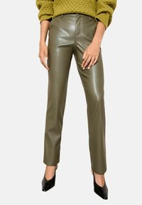 Olīvu zaļas, mākslīgās ādas bikses ar šauru piegriezumu, plakanu priekšpusi un nelielu spīdumu, apvienotas ar melniem norādīto pirkstu papēžiem.