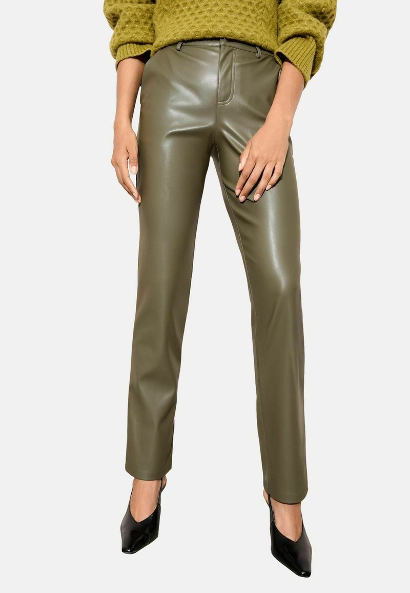 Olīvu zaļas, mākslīgās ādas bikses ar šauru piegriezumu, plakanu priekšpusi un nelielu spīdumu, apvienotas ar melniem norādīto pirkstu papēžiem.