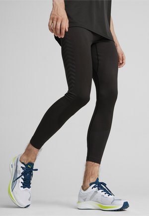 Juodos sportinės legging kelnes su tekstūruotais paneliais ir chevrono raštais, derinamos su baltai pilkais bėgimo batais su mėlynomis detalėmis.