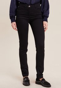 Jean skinny noir en mélange de coton, avec un design classique à cinq poches, fermeture à bouton et une texture lisse.