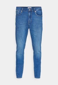 Jean bleu slim fit avec taille mi-haute, en denim. Dispose de cinq poches, coutures ton sur ton et léger délavage le long des jambes.