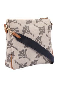 Teksturowana beżowa torba z czarnym wzorem kwiatowym, z akcentami z brązowej skóry i granatowym paskiem. Zapięcie na zamek z złotym okuciem. Prostokątny kształt.