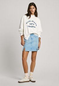 White sweatshirt with "Pepe Jeans 1973 LONDON" in navy, paired with a light blue denim skirt featuring side slits, and white sneakers.
