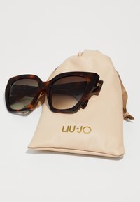 Rjave sončna očala iz tortoiseshell z velikimi, oglatimi okvirji. Priložen bež usnjeni kovček z zlatim logotipom "LIU·JO".