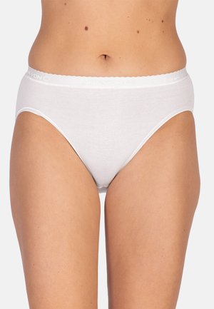 Frau trägt schlichte weiße Baumwoll-Bikini-Unterwäsche, von der Taille bis zur Mitte des Oberschenkels sichtbar, vor einem hellgrauen Hintergrund.