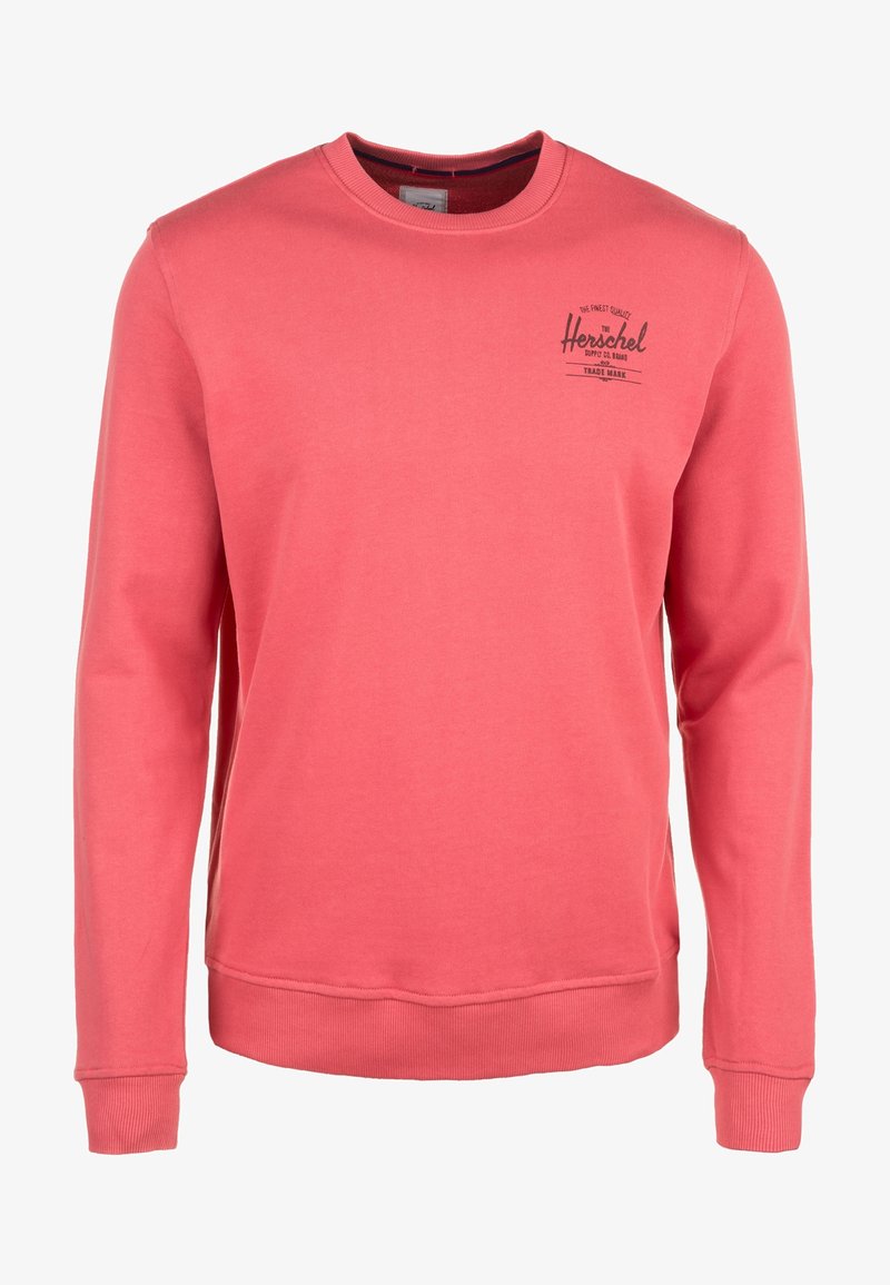 Sweatshirt corail rose à manches longues avec col rond, poignets et ourlet côtelés, arborant un petit logo noir "Herschel" sur le côté gauche de la poitrine.