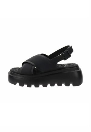 Sandali neri con cinturini larghi incrociati e una fibbia per la caviglia regolabile. Suola spessa e testurizzata con il logo Clarks sulla soletta.