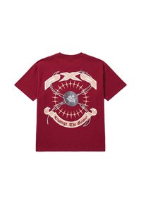 T-shirt rouge avec un motif beige et blanc incluant du fil barbelé, et une bannière avec un texte dans le dos.