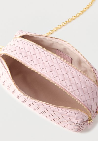Ροζ υφασμένη δερμάτινη τσάντα χιαστί με διπλά χρυσά φερμουάρ ανοιχτά και χρυσή αλυσίδα λουρί σε λευκό φόντο.