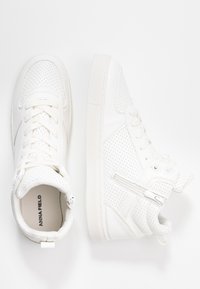 Ein Paar weiße, perforierte High-Top-Sneaker mit Schnürsenkeln und seitlichem Reißverschluss auf weißem Hintergrund.
