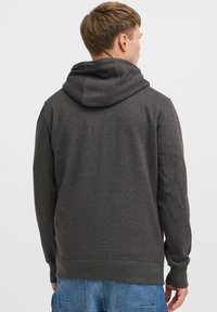 Donkergrijze sweatshirt met capuchon, gestructureerde stof, geribbelde manchetten en zoom, en een eenvoudig ontwerp. Zichtbare stiksels en een lichte kleurvariatie.