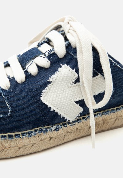 Σκούρο μπλε πάνινο αθλητικό παπούτσι με λευκά κορδόνια, με φθαρμένο λευκό πατζάρι σε σχήμα βέλους στο πλάι και πλεγμένη σόλα από τζουτ.