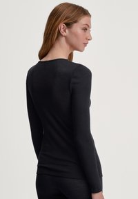 Zwarte longsleeve top van ribbelstof, met een ronde halslijn en aansluitend ontwerp. De textuur is glad en aansluitend.