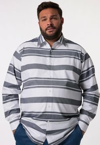 Camisa blanca de botones con gruesas rayas grises. Presenta un cuello con solapas y mangas largas, confeccionada en una tela suave. Ajuste casual.