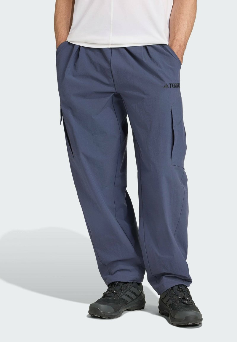 Pantalones cargo exteriores en color navy, hechos de tejido ligero, con bolsillos laterales, cinturilla elástica y un corte relajado, complementados con zapatos negros.