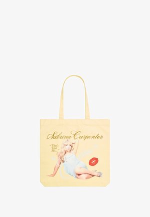 Yellow tote bag made of fabric, featuring printed text including "Sabrina Carpenter" and an image of a woman in a light blue outfit.