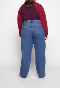 Vaqueros de tiro alto y corte holgado en denim azul medio. Presentan dos bolsillos traseros con costuras sutiles y una etiqueta de cuero de la marca en la cintura.