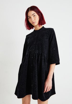 Robe noire à boutons avec une texture douce, comportant une jupe plissée, un col arrondi et des manches mi-longues avec un motif animal discret.