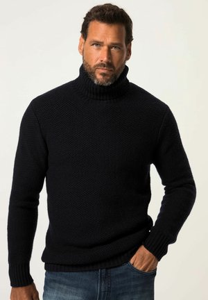 Maglione a collo alto chunky navy realizzato in tessuto a maglia texture con polsini e orlo ribbed. Abbinato a jeans di denim.