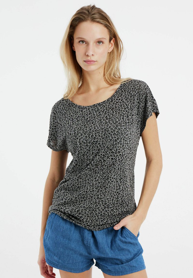 Sort og grå leopardmønstret kortærmet top med en løs pasform og bred udskæring, parret med blå shorts med et afslappet design.