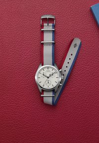 Orologio in metallo argentato con quadrante bianco, tre sotto-quadranti e cinturino in nylon multicolore con strisce rosse, bianche e blu.