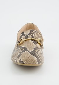 Pohled zepředu na mokasíny v béžové a hnědé barvě s hadím vzorem a zlatým kovovým detailem ve tvaru uzdečky na bílém pozadí.