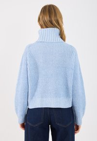 Ανοιχτό μπλε, πλεχτό πουλόβερ με ψηλό ραβδωτό γιακά, υπερμεγέθη εφαρμογή και μακριά μανίκια. Διαθέτει υφασμάτινο σχέδιο και κοπή μέχρι τη μέση.