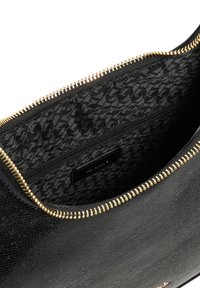 Black textured handbag with gold zipper, showing a patterned interior lining and a small inner pocket. Features a smooth exterior finish.