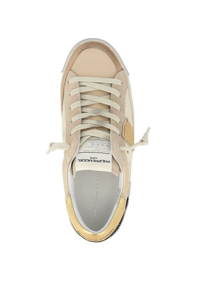 Baskets beiges et crèmes avec des lacets noués en nœuds, étiquette blanche sur la languette portant "Philippe Model Paris", et accent doré sur le col du talon.