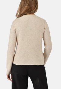 Maglione beige realizzato in morbido tessuto a maglia, caratterizzato da sottili decorazioni, polsini e orlo a costine, e un classico design a girocollo.
