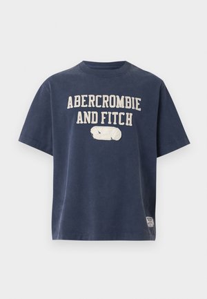 Námornícky modré tričko s krátkym rukávom s textom "ABERCROMBIE AND FITCH" a malou bielou našitou nášivkou pod textom, zobrazené na bielom pozadí.