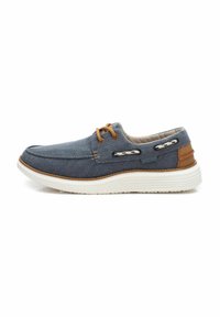 Scarpa in tela blu navy con suola bianca, dettagli marroni e lacci decorativi; presenta una punta arrotondata e un interno imbottito.