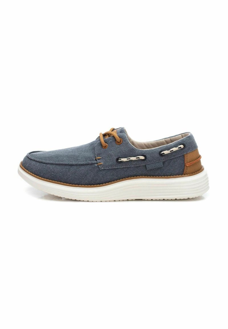 Scarpa in tela blu navy con suola bianca, dettagli marroni e lacci decorativi; presenta una punta arrotondata e un interno imbottito.