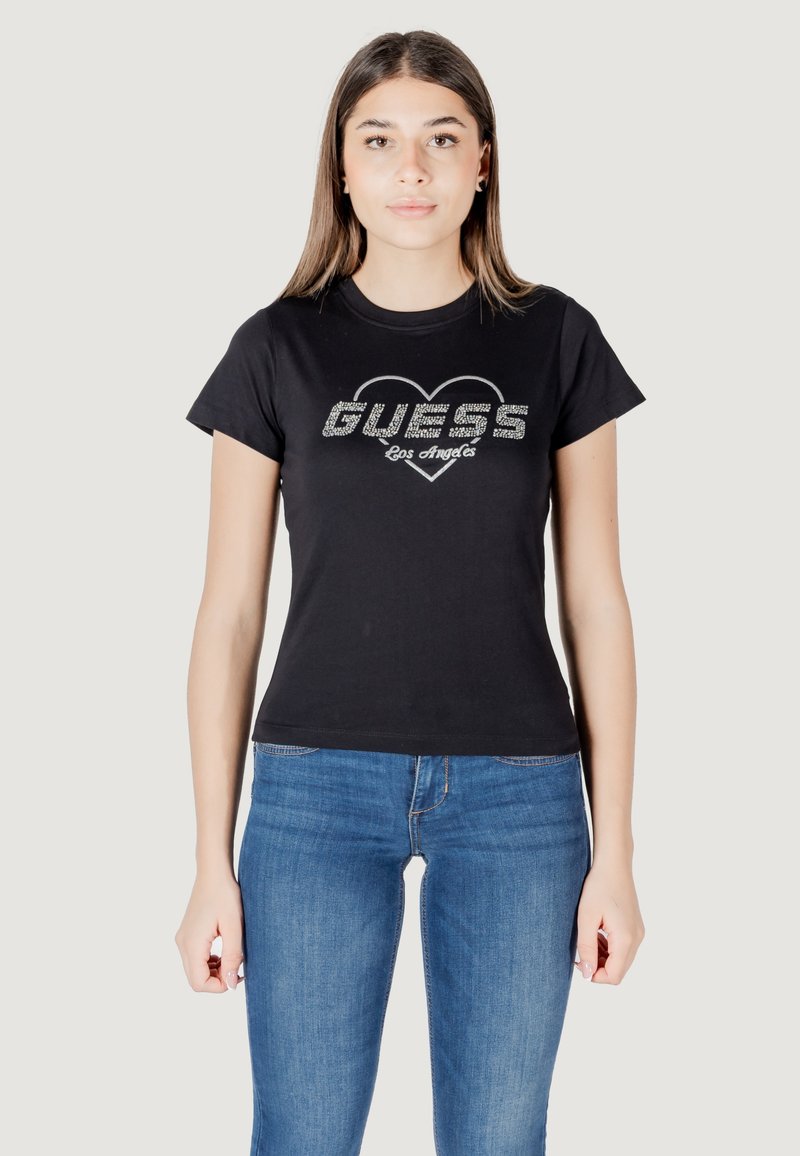 Zwarte katoenen T-shirt met korte mouwen, voorzien van een hartafbeelding en glinsterende "GUESS Los Angeles" tekst op de voorkant. Draag met blauwe jeans.