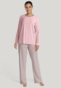 Lichtroze langemouwtop met ronde hals, gecombineerd met gestreepte, zachte pyjamabroek in wit, roze en donkerblauwe horizontale strepen.