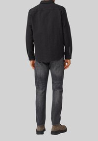 Zwarte button-up shirt met lange mouwen, casual pasvorm en contrasterende stofaccenten op de manchetten. Draagt met donkergrijze jeans en bruine laarzen.