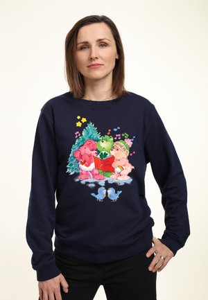 Marineblauwe sweatshirt met kleurrijke cartoonberen die kerstliedjes zingen, een groene boom en blauwe vogels. Ontwerp bevat muzikale noten en een rood boek met de titel "Onze Liedjes."