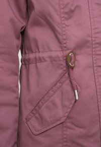 Μωβ μπουφάν με σφιγμένη μέση, τσέπη με καπάκι και κορδόνι που ταιριάζει, με λεπτομέρειες από δέρμα και μεταλλικό περικόχλιο.