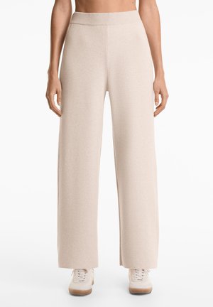 Light beige wide-leg pants made from soft, textured fabric with a ribbed waistband. Designed for comfort, featuring a relaxed silhouette.
