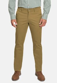 Pantalones de pierna recta en tono beige con una textura suave, diseño de 5 bolsillos y lazos para cinturón, combinados con zapatos marrones y una camisa de cuadros en verde y blanco.