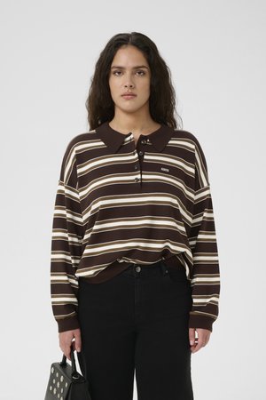 Brown and cream striped long-sleeve polo shirt with a collar, button placket, and ribbed cuffs, paired with black high-waisted pants and a handbag.