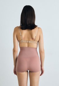 Shapewear a vita alta in tessuto rosa chiaro, con spalline regolabili e una texture liscia. Design senza cuciture con dettagli minimi.