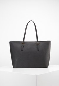 Černá taška přes rameno vyrobená z textured syntetického materiálu, vybavená dvěma uchy a zlatými kovovými akcenty. Obdélníkový tvar s minimalistickým designem.