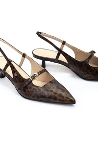 Zapatos tipo slingback con estampado de leopardo, puntera afilada, tacones bajos y una delgada correa en el tobillo con hebilla dorada. Textura suave, colores marrón y negro.
