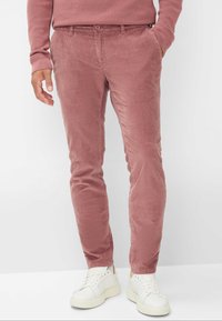 Pantalon en velours côtelé de couleur rose poussiéreux, design ajusté, avec poches avant et passants de ceinture, associé à des baskets blanches et un haut assorti.