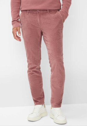 Pantaloni di velluto a coste color rosa polveroso, taglio aderente, con tasche anteriori e passanti per cintura, abbinati a sneaker bianche e a un top coordinato.