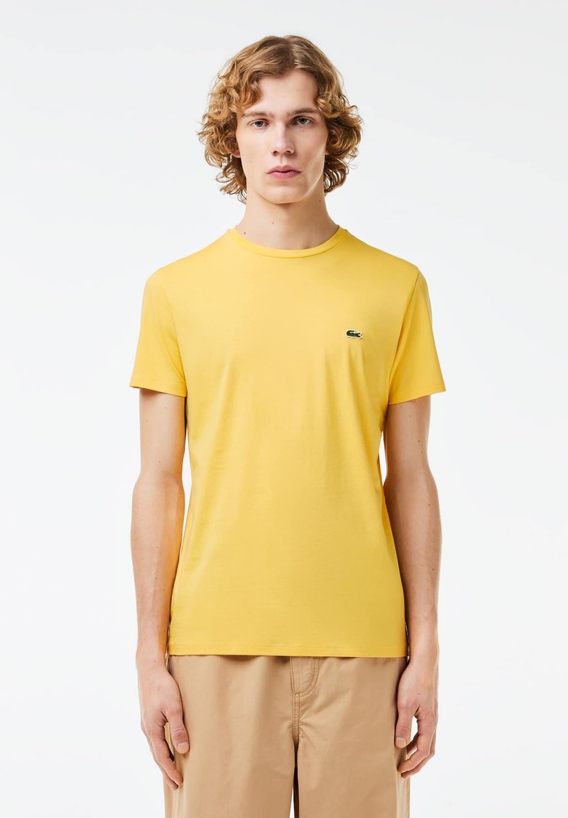 Geel katoenen T-shirt met korte mouwen en een ronde hals, met een klein groen logo op de linkerborst.