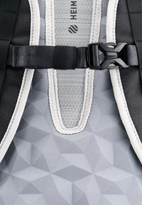 Zaino grigio in materiale con motivo geometrico, dotato di accessori neri, spallacci regolabili e un retro in rete per la ventilazione.