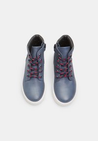 Baskets montantes en cuir bleu avec des lacets rouges, doublure noire et semelles en caoutchouc blanches. Comprend une fermeture éclair sur le côté pour un enfilage facile.