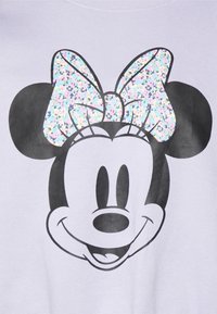 Felpa viola chiaro con una grande grafica di Minnie Mouse in bianco e nero e un fiocco pastello scintillante. Tessuto morbido.